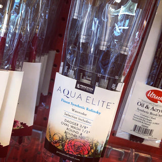 Aqua Elite brush set made by Princeton Artist Brush Company for Blick Art Materials. on a retail display, white label, mostly black text. has TaLisa’s floral ink artwork in red, pink, yellow, green near the bottom of the brush package. 